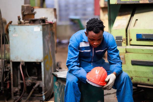 A person wearing a blue overall and gloves holding a hard hat

AI-generated content may be incorrect.